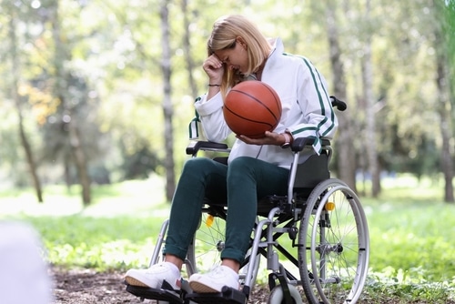 Disabled woman in wheelchair holding basketball ball and crying