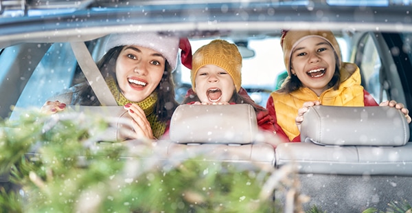 Childen smile from the backseat while parents load the trunk in Fishkill for Christmas