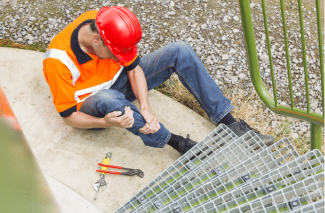 High angle view of mid adult worker suffering from leg pain by storage tank steps in park