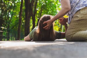 Close up of a woman being helped off of the ground after encountering a sidewalk hazard