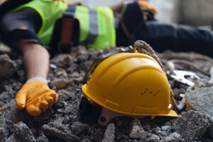 Construction worker laying injured in the foreground, in need of an accident attorney