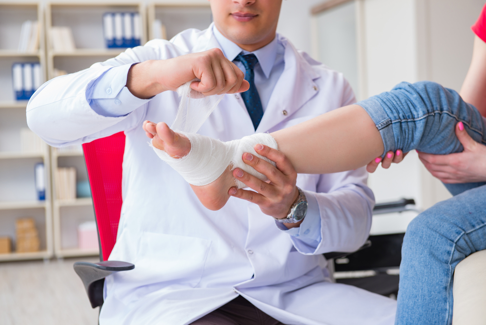 Doctor wrapping a patient's foot after a severe ankle injury due to negligence.