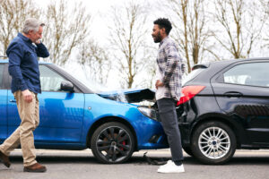 Two men standing in front of a rear-end collision accident, talking about fault