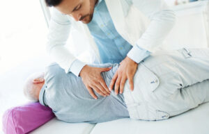 Doctor examining a patient's back after they developed a herniated disc from an accident or work injury.