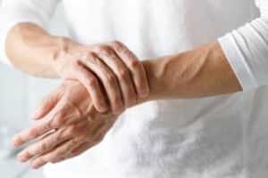 Close up of a worker rubbing and tensing their injured wrist from carpal tunnel syndrome.